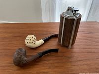 Two pipes and one table lighter arranged on wooden surface