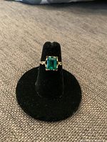 Front view of ring on black velvet stand showing square green stone and band