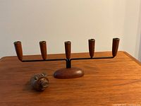 Photo shows a four-candle teak and metal candelabra and a small teak hedgehog figurine with metal ears and eyes on a wooden tabletop.