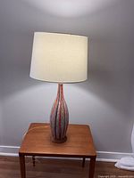 Full view of the MCM retro table lamp with shade on, placed on wooden side table.