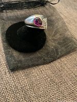 Ring on black display angled to show pear-shaped pink stone and clear accent stones