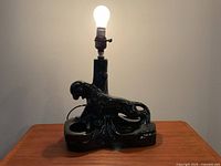 Front view showing black panther ceramic lamp base with bulb illuminated.
