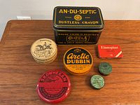 Top view of all seven vintage tins arranged on wood surface, highlighting colors and labels