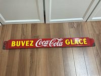 Full-length view of red enamel bar with yellow “BUVEZ” and “GLACÉ” text flanking white Coca-Cola logo