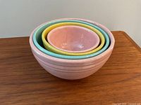Stacked view of four nested bowls showing varying pastel colors and ribbed textures.