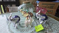 Full grouping of six elephant figurines on lace-covered tabletop