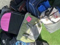 Assorted bags and lunch boxes on balcony floor, showing a pink and black backpack, green reusable bag, blue insulated lunch bag, and white and gray lunch box.