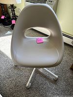 Front view of cream/off-white plastic swivel chair with cut-out backrest and seat, on carpeted floor