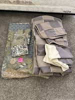 Image showing folded reversible quilt with floral and nature patterns alongside folded comforter with pillow shams and bed skirt on the floor.