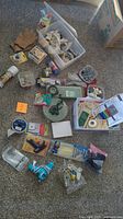 Wide view of all crafting supplies, tools, glue sticks, styrofoam, ribbons, tapes, sewing items spread on carpet