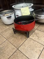 Photo showing white rice steamer, Smart Pot crock pot, red fondue pot with stand, and stainless steel electric skillet on tiles.