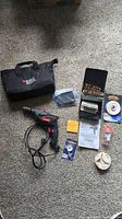 Overview of all items in the lot including drill, drill bit set, accessories, gloves, carrying case, and paperwork.