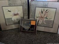 Three framed floral paintings arranged with two larger square paintings and one smaller rectangular painting in front