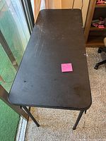 Top view of the black rectangular folding table showing surface scratches and wear marks.
