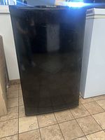 Front view of the black Frigidaire mini fridge showing minor surface scratches