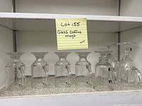 Photo of the six clear glass coffee mugs inverted showing their shape and handles.