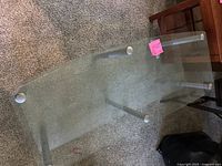 Top view showing glass table with silver cylindrical legs on carpeted floor