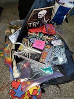 Photo showing Halloween skeleton decoration, costume props, and boxed Halloween accessories inside a suitcase.
