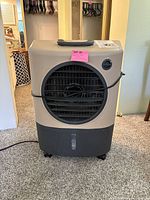 Front view of the Hessaire MC18M portable evaporative cooler with visible large circular vent and power cord wound around front.