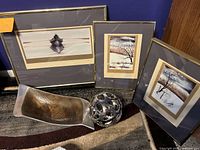 Three framed paintings and two decorative metal accessories arranged together