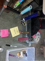 Photo showing six different kaleidoscopes on a glass table, one black with red end, colorful geometric design, brass-colored tube, blue tube, polka dot tube, and small silver tube