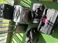 Overview of all luggage items and cart on balcony floor with sunlit green artificial grass.