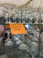 12 martini glasses and 3 wine glasses displayed on glass shelf with sticker noting lot number and contents
