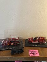 Photo showing 1931 Seagrave Fire Truck model, 1941 GMC Fire Truck model, and Train Engine RM 2 model on flat surface with note