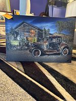 Front view of the canvas showing an old rusted car parked near a Shell gas station with desert plants and hills in the background.