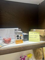 Shelf with various outlet adapters and extension cords, some in packaging, some loose, with post-it note identifying lot