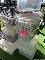 Stacked assortment of plastic storage bins and baskets on a balcony, showing different sizes and some lids in varying colors.