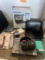 Full lot showing Philips portable DVD player with case, MPOW headphones, J3 wireless earbuds, e-Circuit mini powered speaker, charger wires, TV antenna and other power cords.