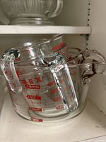 Four Pyrex glass measuring bowls stacked, showing red measurement marks including 1 cup, 2 quarts, 4 quarts