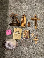 Overview of all religious decor items arranged on carpet including crosses, statues, angels, plaques, rosary.