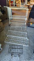 Assorted wire racks of various sizes and styles placed on carpet in front of rolling cart