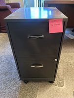 Front view of the small metal file cabinet with two drawers and wheels, showing a lock on the lower drawer and silver handles.