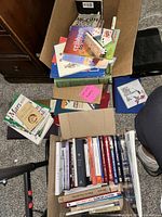 Photo of boxed and stacked books showing a variety of titles and genres including religious, self help, and travel.
