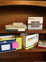 Shelf with stacked stationery boxes and loose envelopes including a box labeled Sympathy Cards