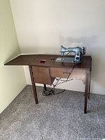 Full view of the sewing machine installed in a wooden cabinet with side table extended.