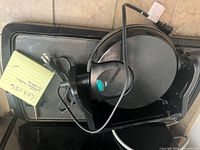 Photo showing the black waffle maker resting on the electric griddle. Waffle maker has a circular shape with an indicator light and attached power cord.