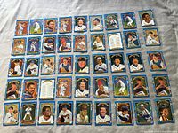 Photo showing 39 cards spread out on fabric, each has blue and gold framing featuring a mix of painted portraits and action shots of baseball players from the 1990 Donruss Diamond Kings series.