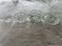 Photo of four crystal dishes: three small open dishes lined up and one round covered dish with a lid.