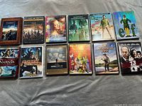 Photo showing a selection of 12 DVDs and Blu-rays from the lot including The Hobbit Trilogy, The Magnificent Seven, Elf, Breaking Bad, Saving Private Ryan, and others.