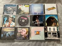 Photo of 12 assorted music CDs including artists Saga, Amy Winehouse, The Killers, Roxy Music, Van Halen and others.