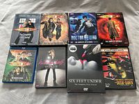 Photo showing 8 DVD and Blu-ray cases featuring TV series and movies, including multiple Doctor Who series, Friends complete series, Hilary Duff, Six Feet Under, and From Dusk Till Dawn.