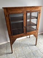 Full front view of the pie safe showing two mesh-front doors, three interior shelves, and tapered legs