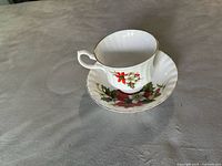 Bluebird brand bone china cup and saucer with red poinsettia floral pattern, white background, scalloped edge, gold trim, made in Canada