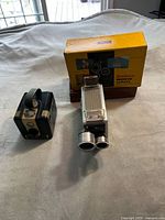 Three vintage Brownie cameras displayed alongside original box and case on white cloth background.