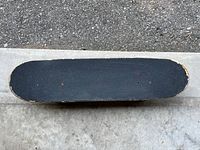 Top view of skateboard showing black grip tape with worn edges.