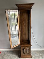 Furniture piece, dark wood grandfather clock style display cabinet with open top glass door showing empty interior, missing shelves